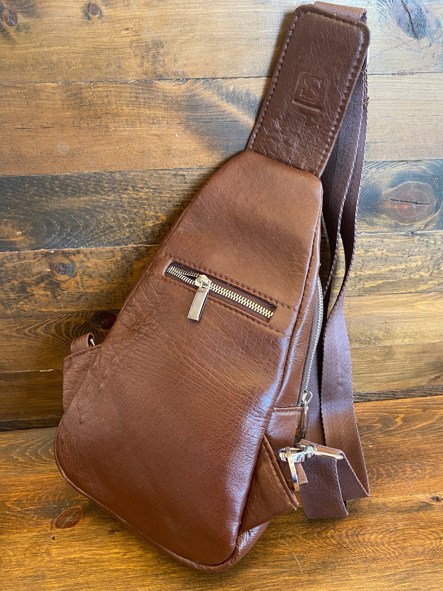 Brown ostrich sling bag. / Bolso avestruz